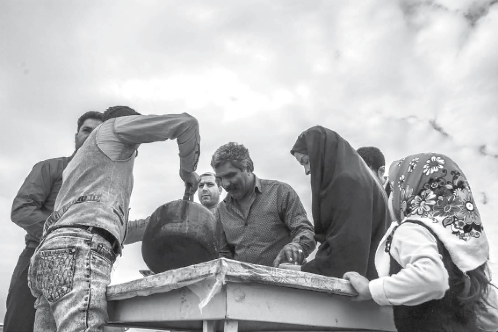 چند نفر در حال هم زدن دیگ غذا 